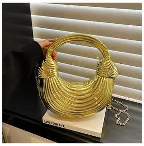 Detail of a golden crescent handbag with textured metallic surface and ring handle