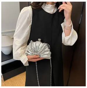 Detail of silver shell-shaped evening clutch with metallic beads and chain strap