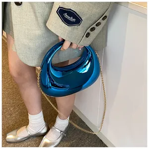 Gros plan d'un sac demi-lune bleu métallique avec finition chromée et chaîne dorée