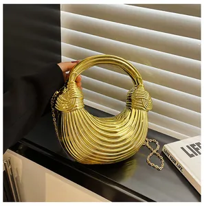 Detail of golden crescent handbag showing 3D pleated texture and metallic ring handle