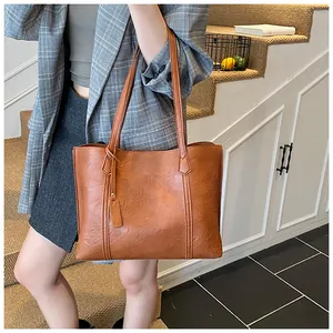 Detail of caramel leather tote bag with long straps and side tag in minimalist design