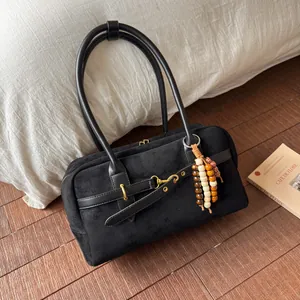 Detail view of black matte suede shoulder bag with colorful wooden bead charm and long straps