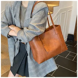 Side view of model wearing a large brown faux leather tote bag with elegant top stitching