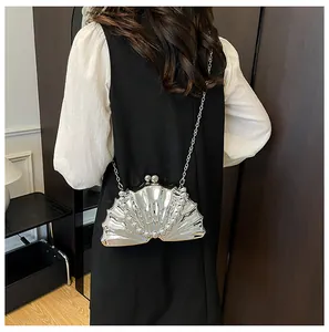 Close-up of a silver shell-shaped evening bag with metallic texture and chain strap