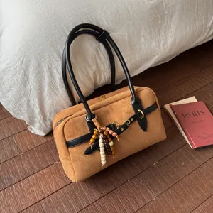 Close-up of brown frosted texture handbag with black straps and wooden bead charm detail