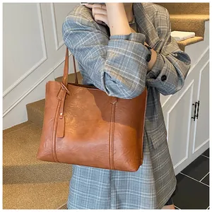 Close-up of vintage brown leather tote bag with dual straps and stitching detail