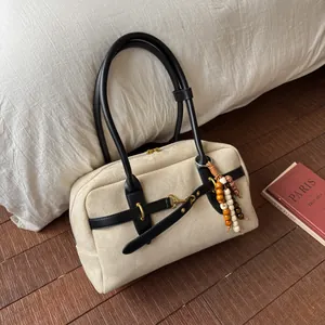 Detail of cream boston bag featuring black leather straps and colorful wooden bead charm