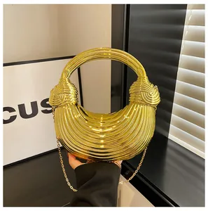 Detail of gold metal half-moon handbag with wave texture and round handle design
