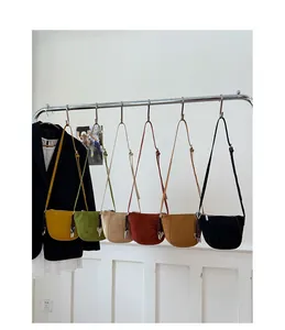 Reihe bunter Leder-Umhängetaschen im Halbkreisdesign, die an einer Wand hängen