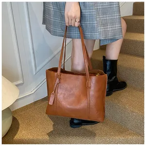 Detailed texture of brown PU leather tote bag featuring a decorative tag and long straps