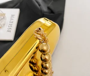 Dettaglio di borsa a mano in acrilico a specchio dorato con cerniere e catena a sfere