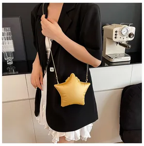 Detail view of yellow star-shaped crossbody bag with gold chain strap on a female model