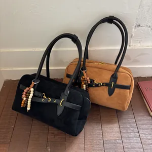 Detailed macro of suede Boston bags in black and tan with ethnic wooden beads and long handles
