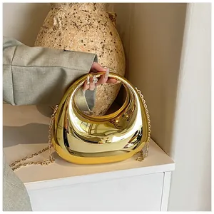 Détail du sac à main en acrylique doré miroir avec poignée ronde et bandoulière chaîne