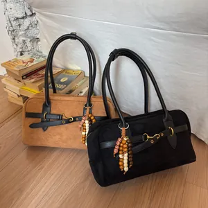 Detail of brown and black suede handbags featuring gold buckles and beaded charms