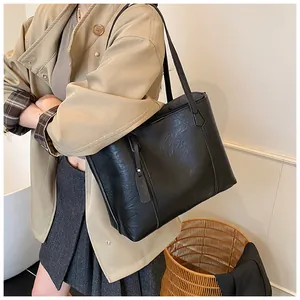 Detailed view of black faux leather tote bag with long handles for shoulder or hand carry