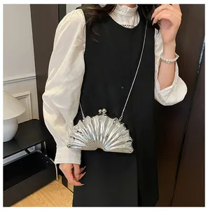 Silver shell-shaped acrylic evening clutch bag shown worn by model with chain strap