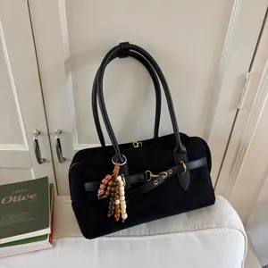 Detail of black suede satchel with gold buckle and decorative wooden beaded charm
