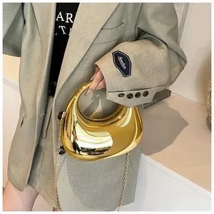 Gros plan d'une pochette demi-lune dorée brillante avec chaîne fine et finition miroir
