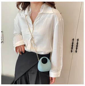 Detail van lichtblauwe mini crossbody tas van acryl met gouden ketting en handgreep