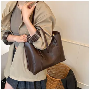 Detailed view of a dark brown large tote bag worn by a model in a natural setting
