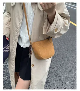 Außenaufnahme einer braunen Wildleder-Mini-Umhängetasche im Vintage-Stil für Damen