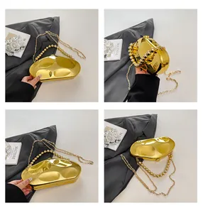 Dettaglio di pochette da sera dorata a specchio con manico di perle e catenina