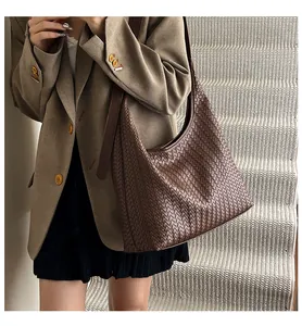 Detail of dark brown woven leather hobo bag worn by model on white stairs