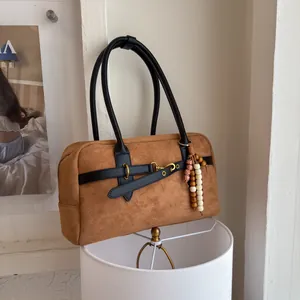 Detail of vintage brown suede handbag featuring black leather trim and wooden bead tassel