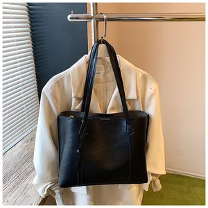 Detail shot of the black leather tote bag with fine grain texture and dual long shoulder straps