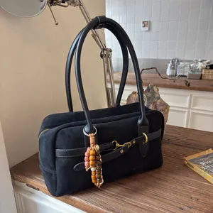 Detail of suede crossbody bag with gold horsebit hardware and vintage beaded charm