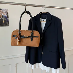 Detail of a brown suede Boston bag with black leather straps and colorful bead charm