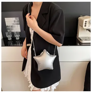 Silver star-shaped crossbody bag with metallic finish and chain strap worn by a model