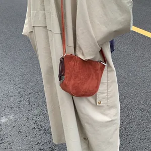 Detailansicht der karamellfarbenen Wildleder-Beuteltasche mit Herzanhänger und Schultergurt