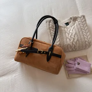 Detailed shot of brown suede Boston bag with black leather handles and beaded charm decor