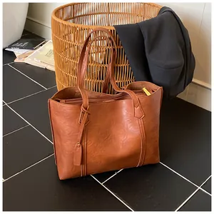 Macro detail of caramel brown faux leather tote bag with stitching on marble floor
