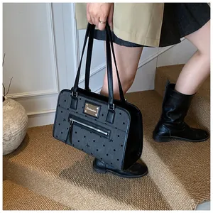 Détail du sac en toile grise à pois avec broderie porté à l'épaule par le mannequin