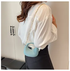 Zijaanzicht van een lichtblauwe halve maan crossbodytas met gouden ketting op model