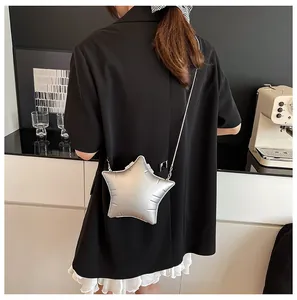 Star-shaped silver crossbody bag with puffy design and snake chain shown in cafe setting