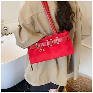 Détail d'un sac d'épaule en daim rouge avec sangle en cuir élégante et boucle dorée