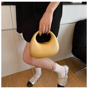 Detail einer gelben Sichel-Handtasche mit goldener Kette und glatter matter Textur
