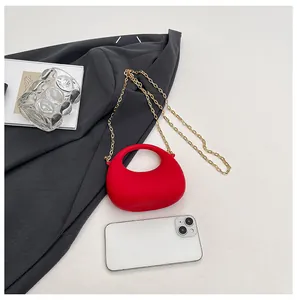 Detail van rode mini handtas met gouden ketting en smartphone voor maatvergelijking