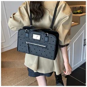 Détail du sac à dos gris à pois avec plaque logo métallique et motifs de nœuds