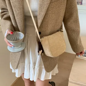 Detail der beigen mattierten Leder-Satteltasche mit Herzanhänger auf Wollsakko
