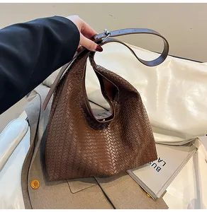 Detail shot of brown woven hobo bag with adjustable leather strap and silver buckle