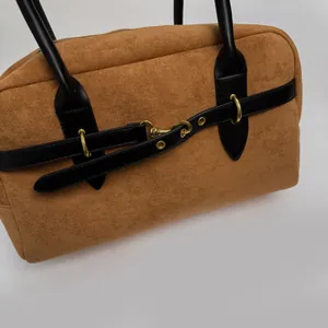 Close-up of retro brown suede handbag with black leather straps and gold metal hardware