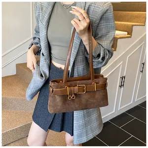 Détail d'un sac à bandoulière en daim marron avec boucle dorée et texture en cuir mat