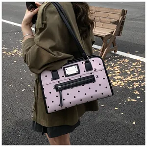 Détail du sac bandoulière rose à pois avec broderies nœuds et plaque logo argentée