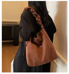 Detail of a brown corduroy tote bag featuring a unique pleated cloud-style wide shoulder strap