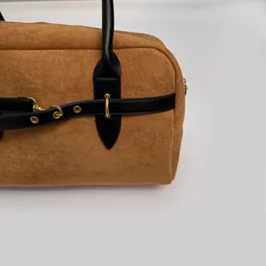 Detail of caramel suede tote with black leather trim and golden metal hardware ring